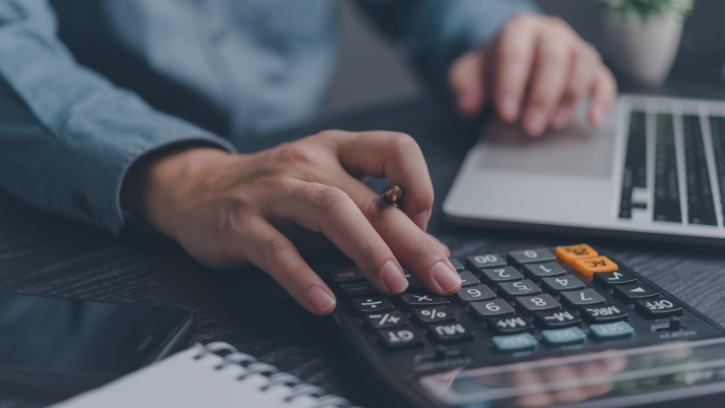 Person using calculator while working on computer